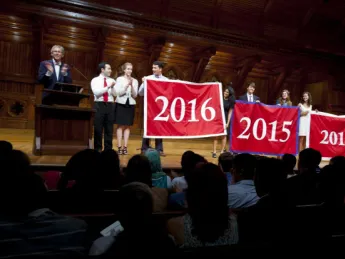Harvard Alumni Association president Carl Muller ’73, J.D.-M.B.A. ’76 (at left), presents the Class of 2016 with its official banner during the Sanders Theatre portion of Freshman Convocation. 