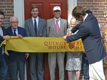 Geyser University Professor emeritus Henry Rosovsky (at left) and members of the Stone family, including grandson Robert Stone ’12, Gregg Stone ’75, J.D. ’79, Marion (Rockefeller) Stone, and Jennifer P. Stone ’80, M.D. ’86, together with Quincy residents Franco Iudiciani ’16 (far left) and Onyeka Nnaemeka ’16 (obscured at right), witnessed grandson Eric Green ’16 cut the ribbon that officially opened Stone Hall’s F entry.