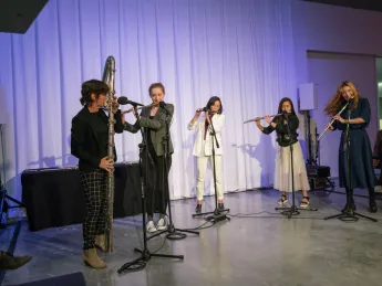 Five flutists playing together on stage  
