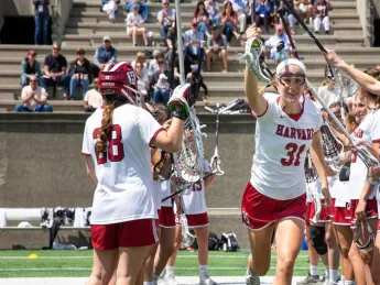 Photograph of Harvard women lacrosse players celebrating.