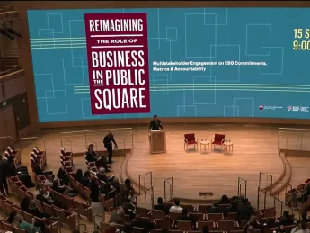 Audience members sit in a large auditorium at the start of the conference