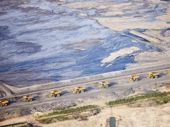 Huge dump trucks lined up in 2012 to transport tar sand from a surface mine, Fort McMurray, Alberta 