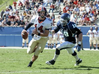Conner Hempel (14), making his first start at quarterback, threw four touchdown passes as Harvard opened the season with a victory over the University of San Diego. The pursuing defender is end Blake Oliaro. 