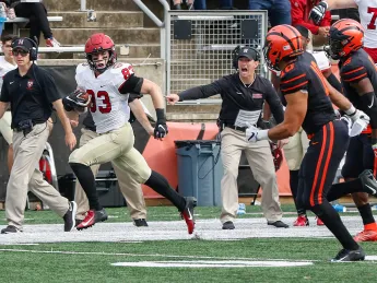 Harvard wide receiver runs up field, away from Princeton defenders.