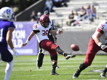 The Harvard punter kicks the football