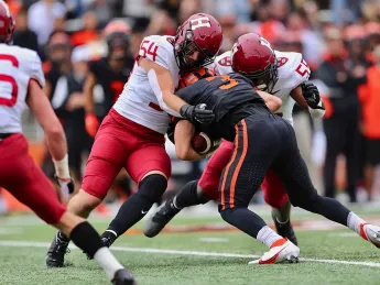 Two Harvard linebackers tackle a Princeton receiver