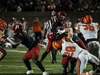 Harvard quarterback Charlie Dean gets off a pass despite Princeton rush.