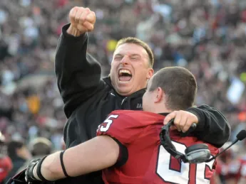 Defensive line coach Michael Horan and reserve tackle Adam Riegel ’13 share a jubilant hug after a 34-24 victory in The Game.