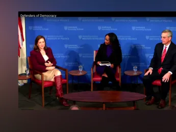 The three speakers are seated on stage at Harvard's JFK Forum.