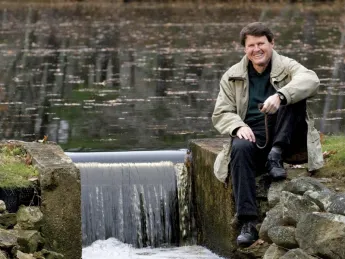 When not dealing with major global water issues, John Briscoe manages this small dam near his home. He holds the hook used to open the sluice gate.