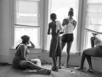 While being evicted from her Milwaukee apartment, Danielle Shaw (left) and relatives wait until the movers carrying down her refrigerator and stove are no longer blocking the stairwell. 