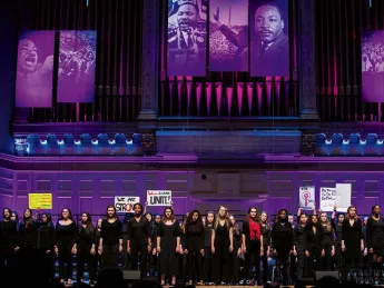 Children singers performing on stage with purple lighting 