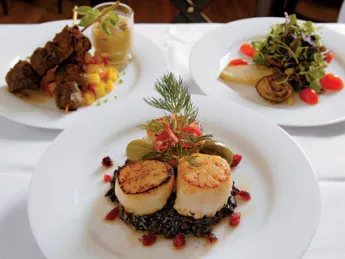 Scallops atop black sticky rice; behind, beef satay and baby greens