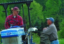 Leaning on one of the operation's eight tractors, he talks with Sam Hammer, a young farmer who works with the Bemis brothers.