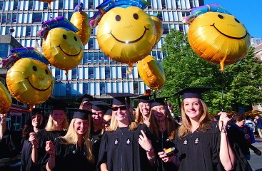 happy graduates posing with balloons by Holyoke Center