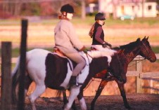 Medical student Cecily Vanderspurt (left) and graduate student Jasna Vellovic ride in an equitation class. Top: a rider pats her horse. Middle: Chris Laumann '03, on 'Hanover,' practices good riding posture with a viewing mirror. Bottom: Riding coach Alyce McNeil with a student. All photos at Verrill Farm, Concord, Massachusetts. DECK for the story: The Harvard Equestrian Club can fly in the saddle. 