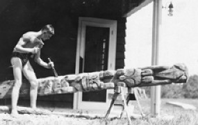 old photograph: young man, wearing only briefs, carving a totem pole