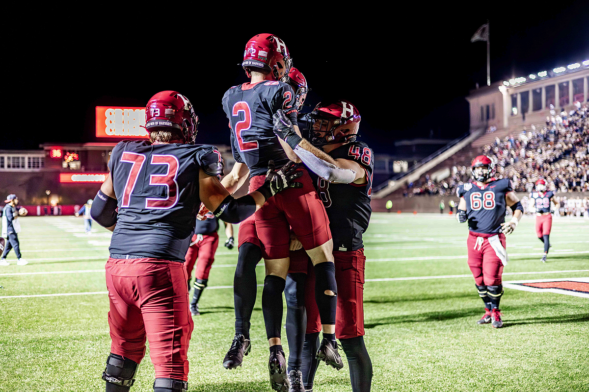 Harvard football players celebrate on the field at Harvard Stadium