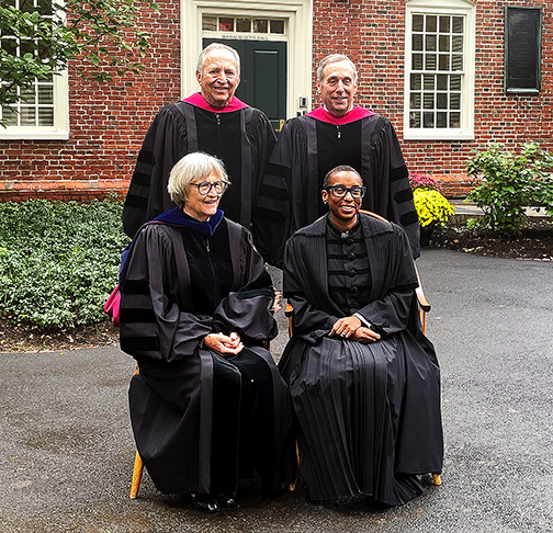 4 people standing in academic robes for photo op