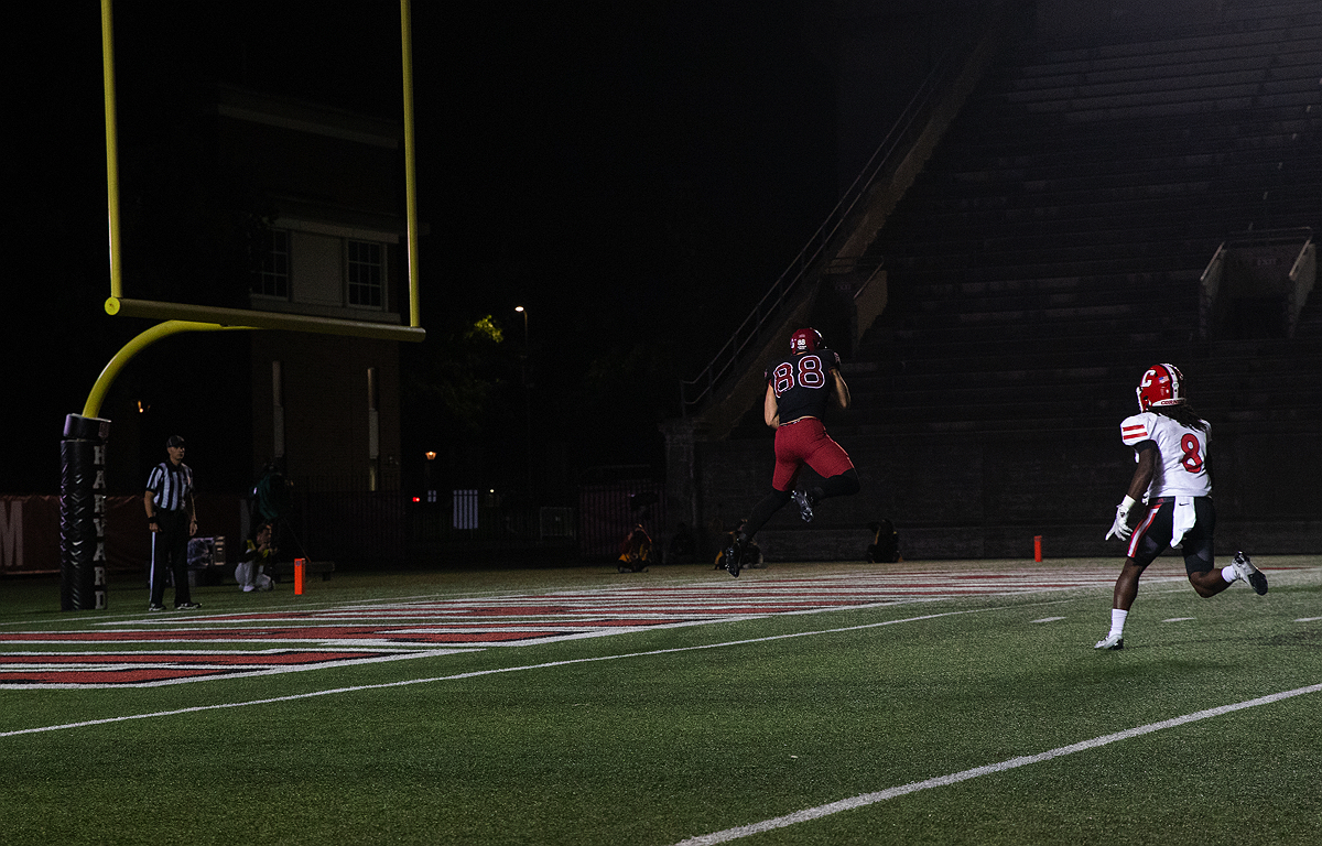 Harvard player leaps up to catch the ball in the end zone with Cornall player in pursuit