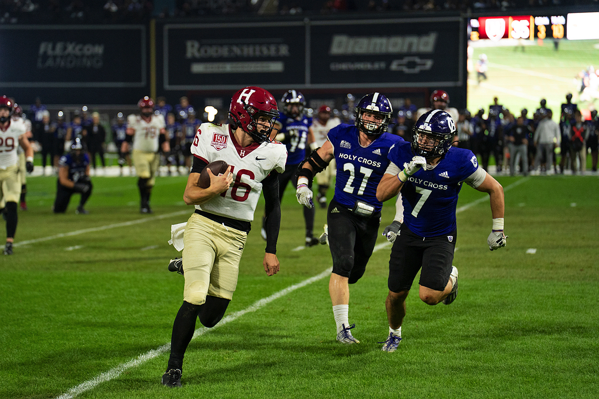 Harvard player running with ball with Holy Cross players in pursuit