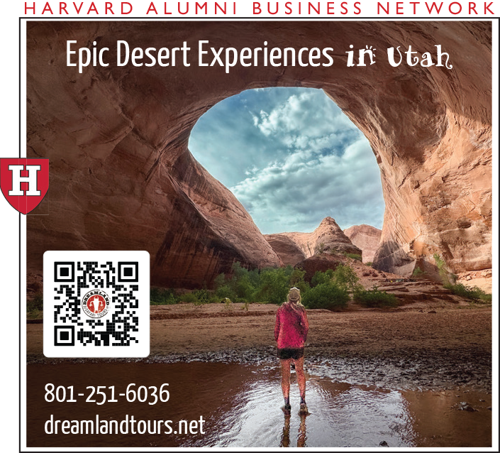 A person stands in a desert canyon, framed by a large rock arch under a blue sky.