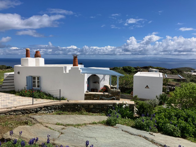 Whitewashed houses with clay chimneys overlooking a serene blue sea and cloudy sky.