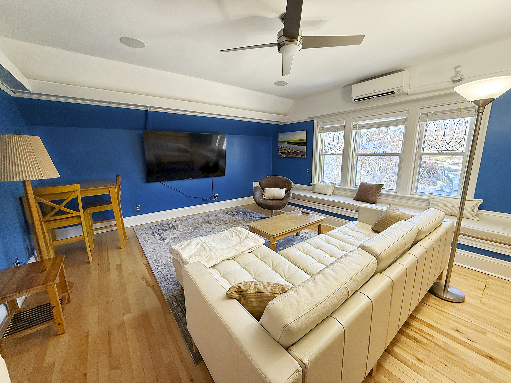 Bright living room with a blue accent wall, white sofa, and a wooden TV stand.