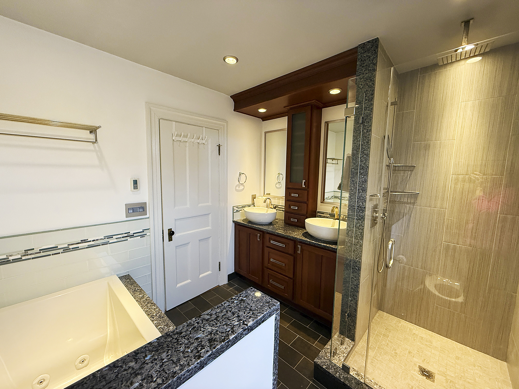 Modern bathroom featuring a sleek shower, wooden vanity, and dual sinks.