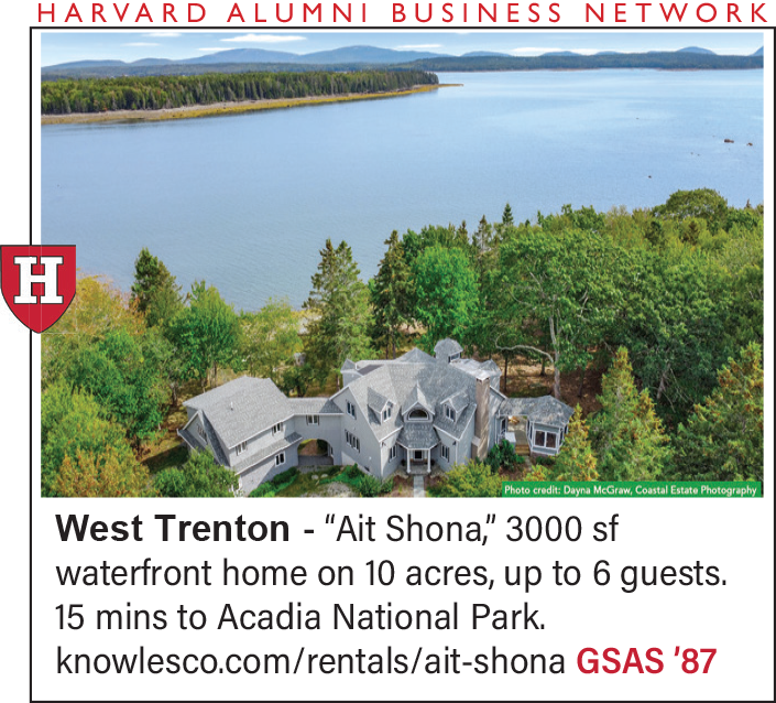 Aerial view of a large waterfront home surrounded by trees and water.