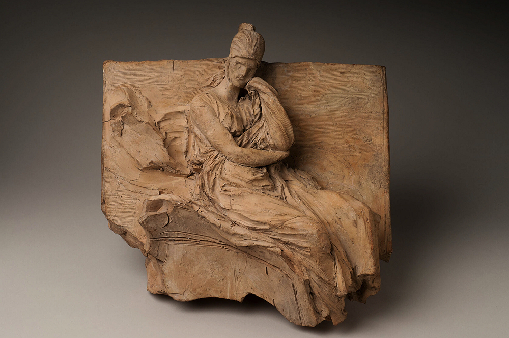 A sculpture of a seated figure resting his face on his hand in thought. 