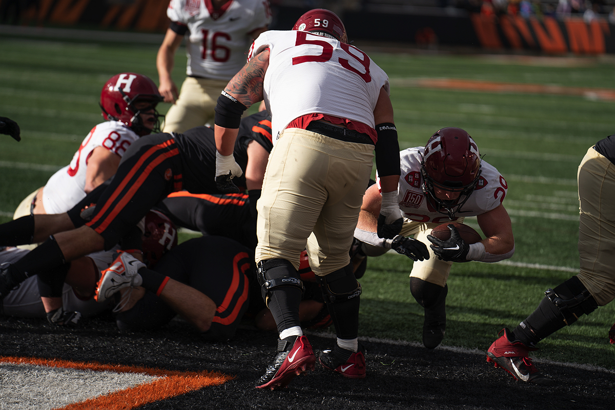 Harvard player with ball is tackled by Princeton players