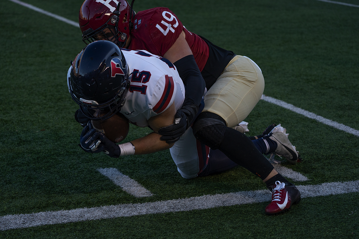 Harvard player tackles Penn player who has the ball