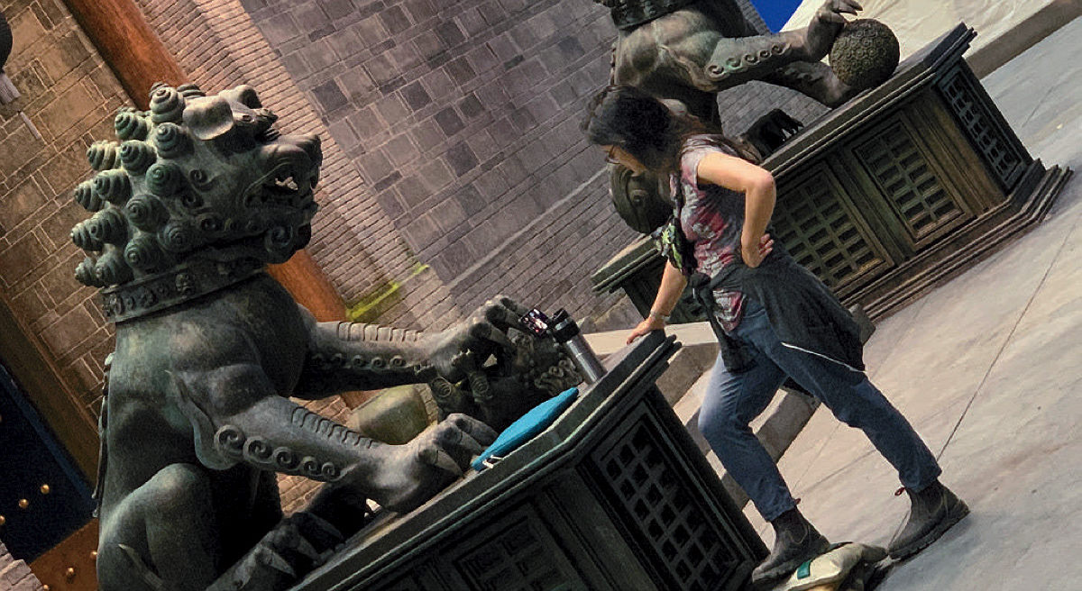 A woman stands next to two large statues of seated lions