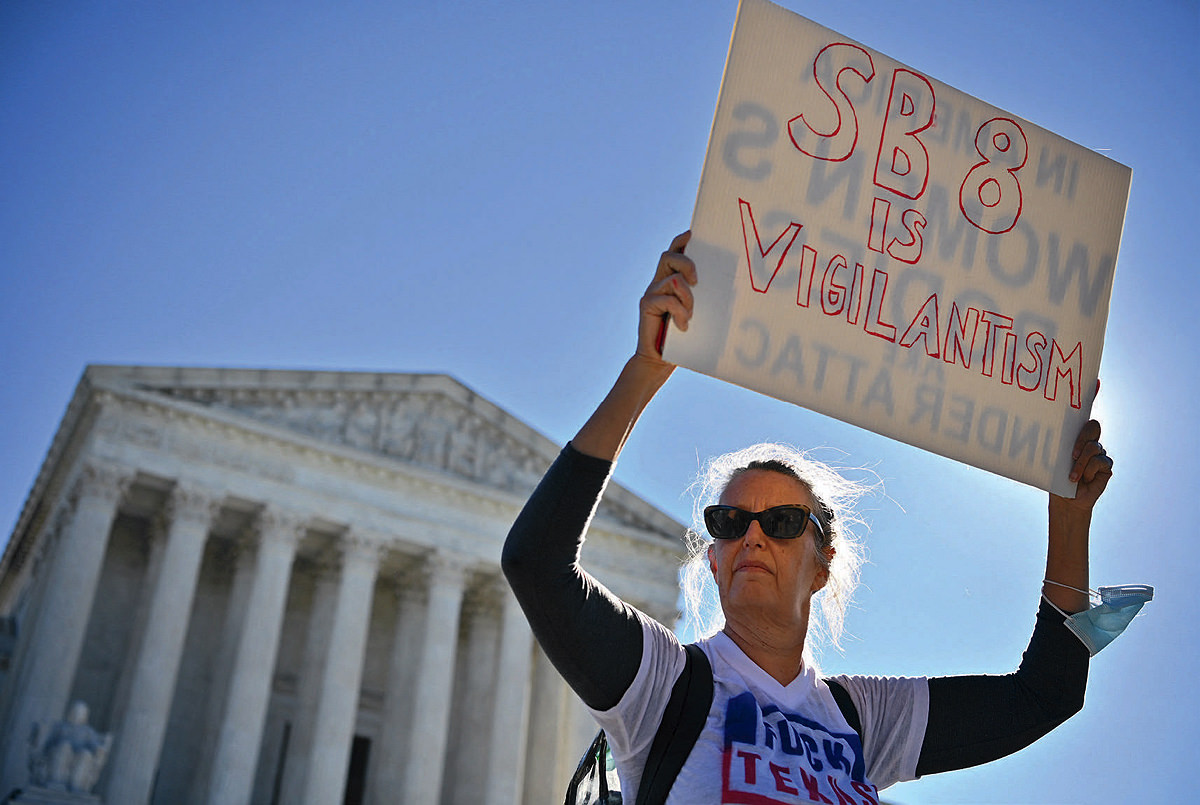 A woman holds up a sign in front of the U.S. Supreme Court to protest Texas SB-8
