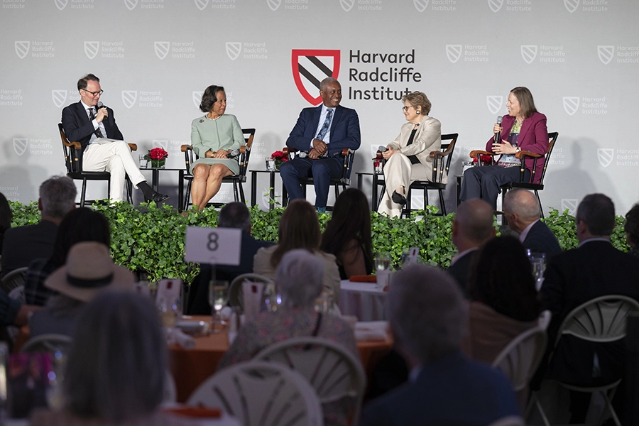 a panel of two men and three women sitting on a stage in front of an audience