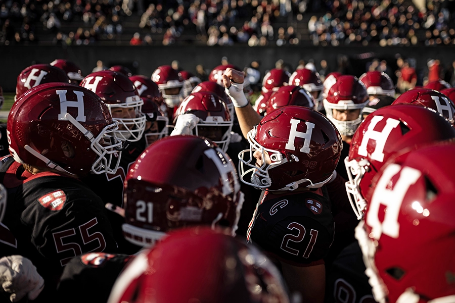 Harvard football players huddle in a circle