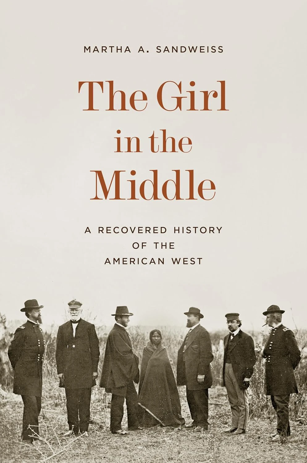 Book cover for "The Girl in the Middle: A Recovered History of the American West" by Martha A. Sandweiss, with a photograph of six men in suits and hats and a young woman in the middle in Native American dress 
