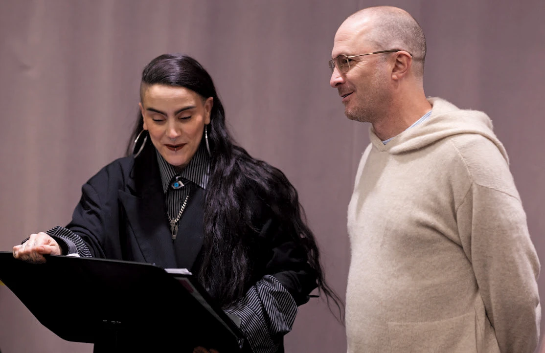 Sonya Tayeh and film director Darren Aronofsky reading from a script on a stand 