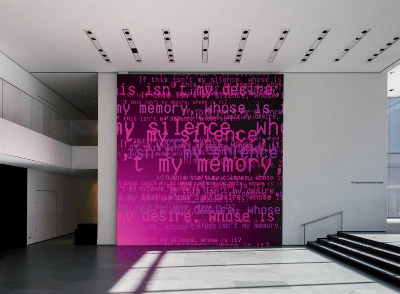 Large pink wall with text on it in an art gallery
