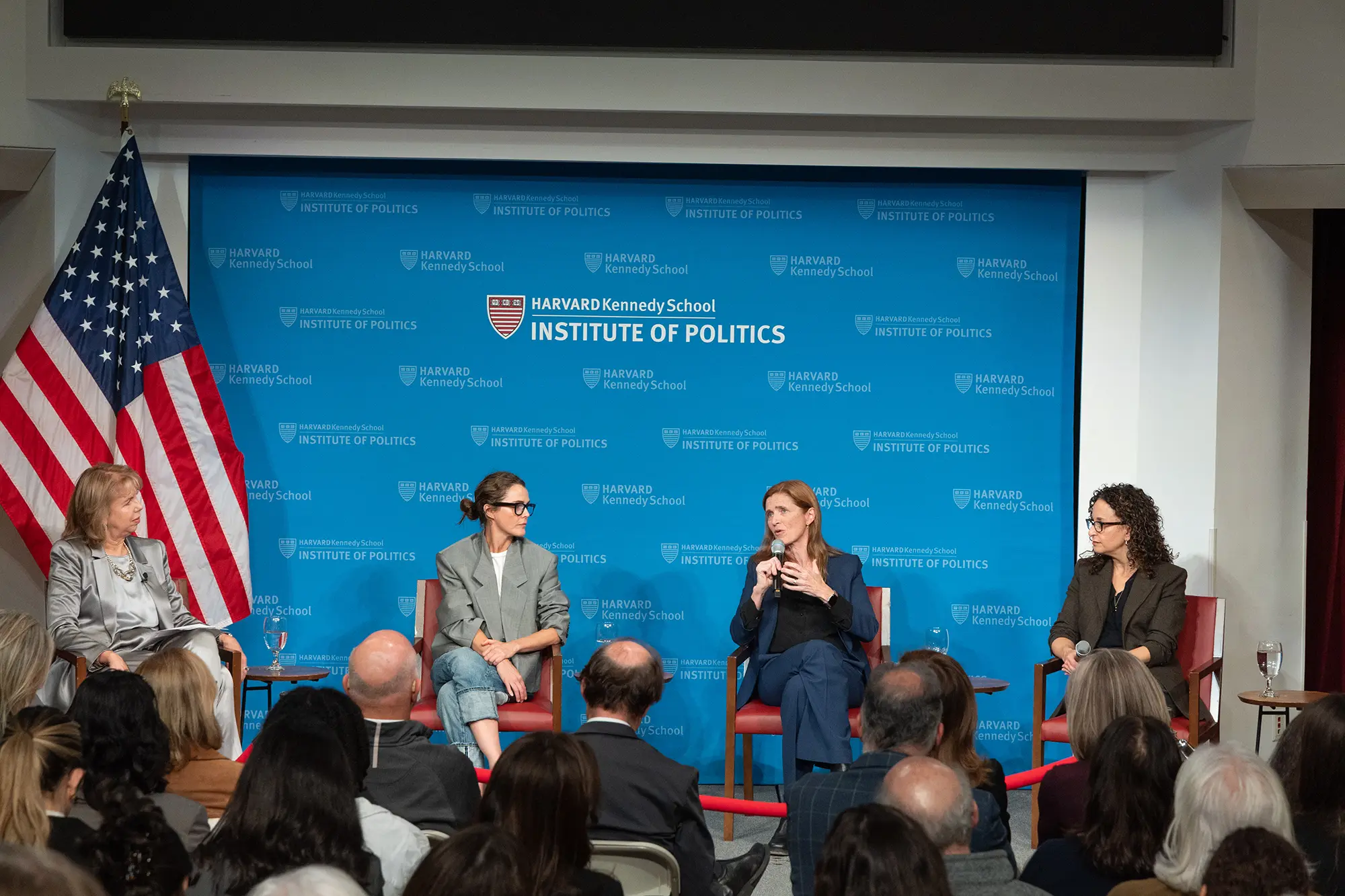 Four panelists sit with the Institute of Politics in the background