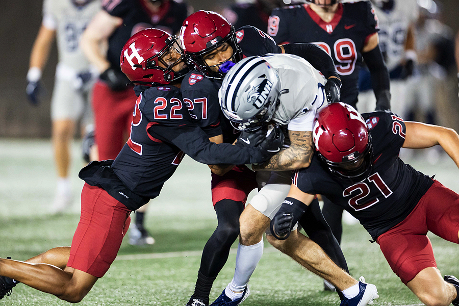 Harvard playes 22, 27 and 21 tackle UNH player who has the ball