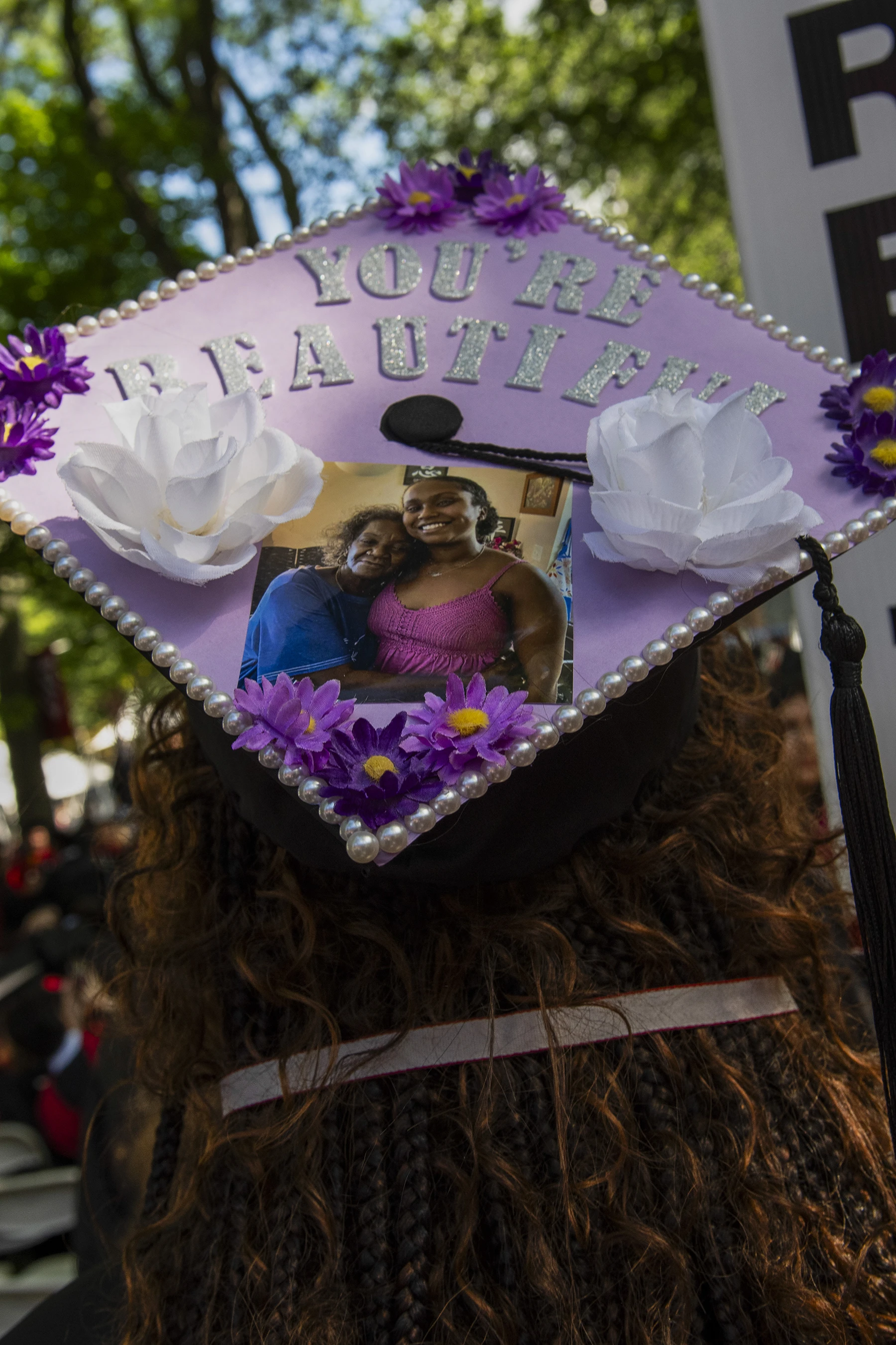 Purple graduation cap decorated with pearls and flowers with a photograph of two women smiling and the text "You're Beautiful"