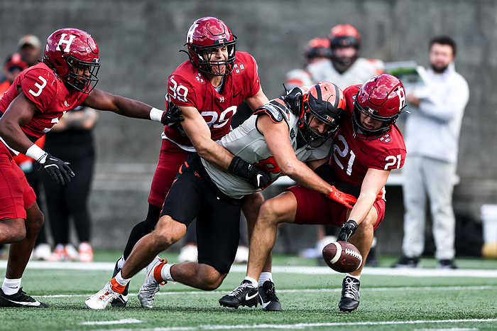 Harvard player #39 holds back Princeton player who is trying to intercept Harvard player #21 who has the ball