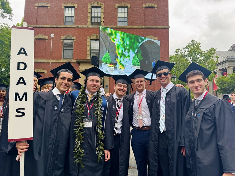 group of students gather in Harvard Yard wearing regalia