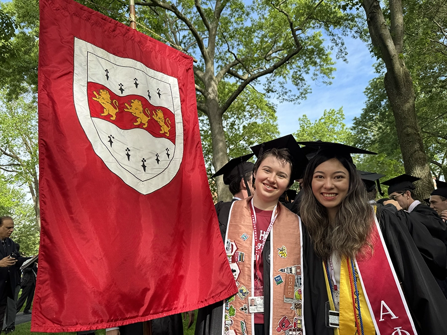 students holding a Harvard house flag and gathering in Harvard Yard wearing regalia