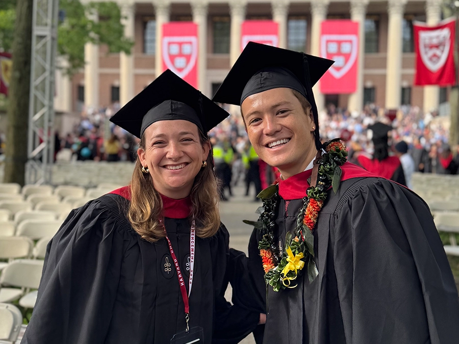 harvard students pose in Tercentenary Theater wearing regalia