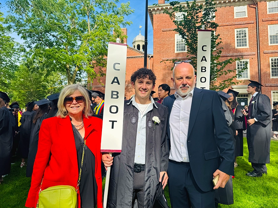 harvard graduate holding a cabot house sign with family