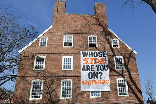 Massachusetts Hall, with a sign "Whose side are you on? #divestharvard"