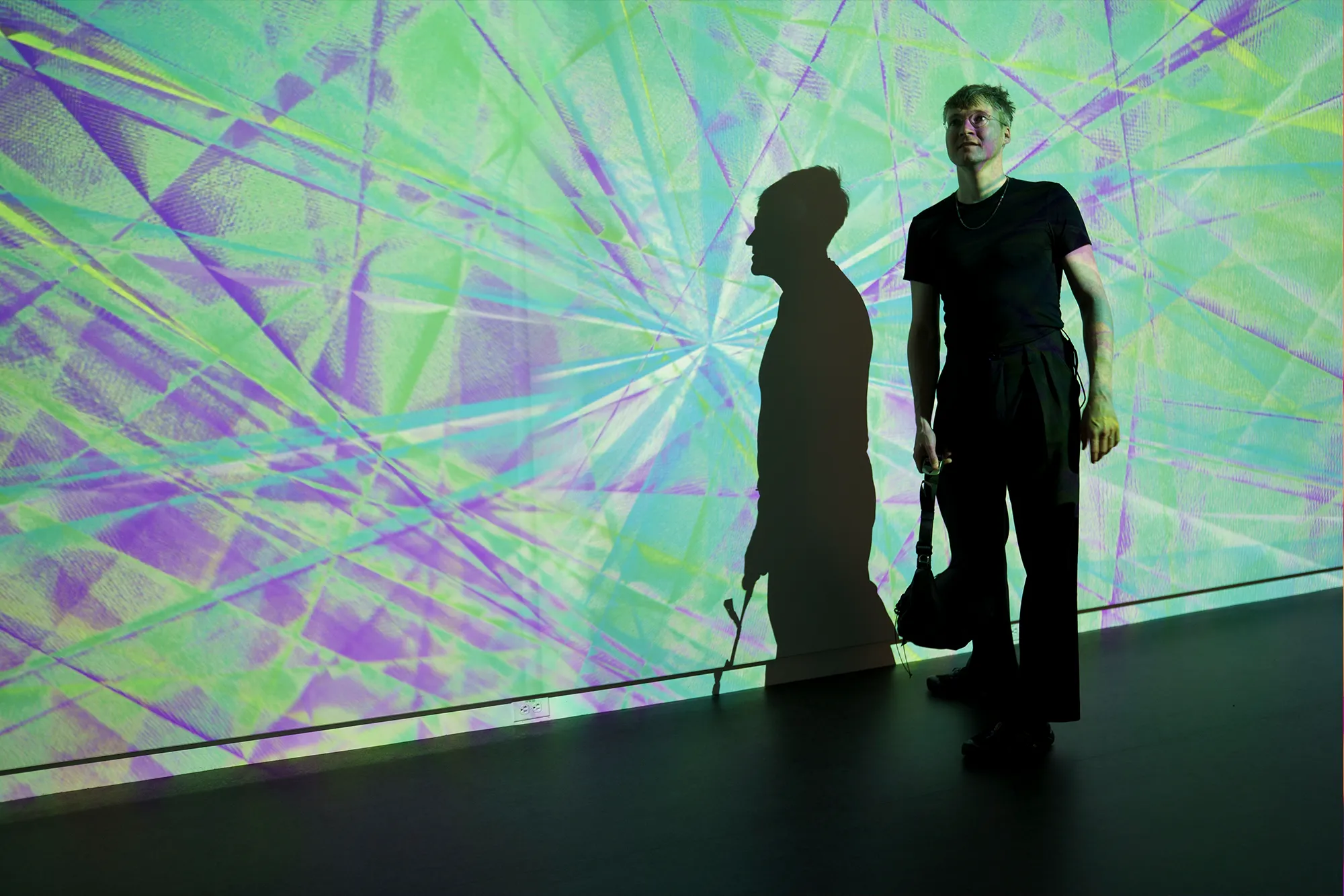 Kim Albrecht stands in front of data visualization art